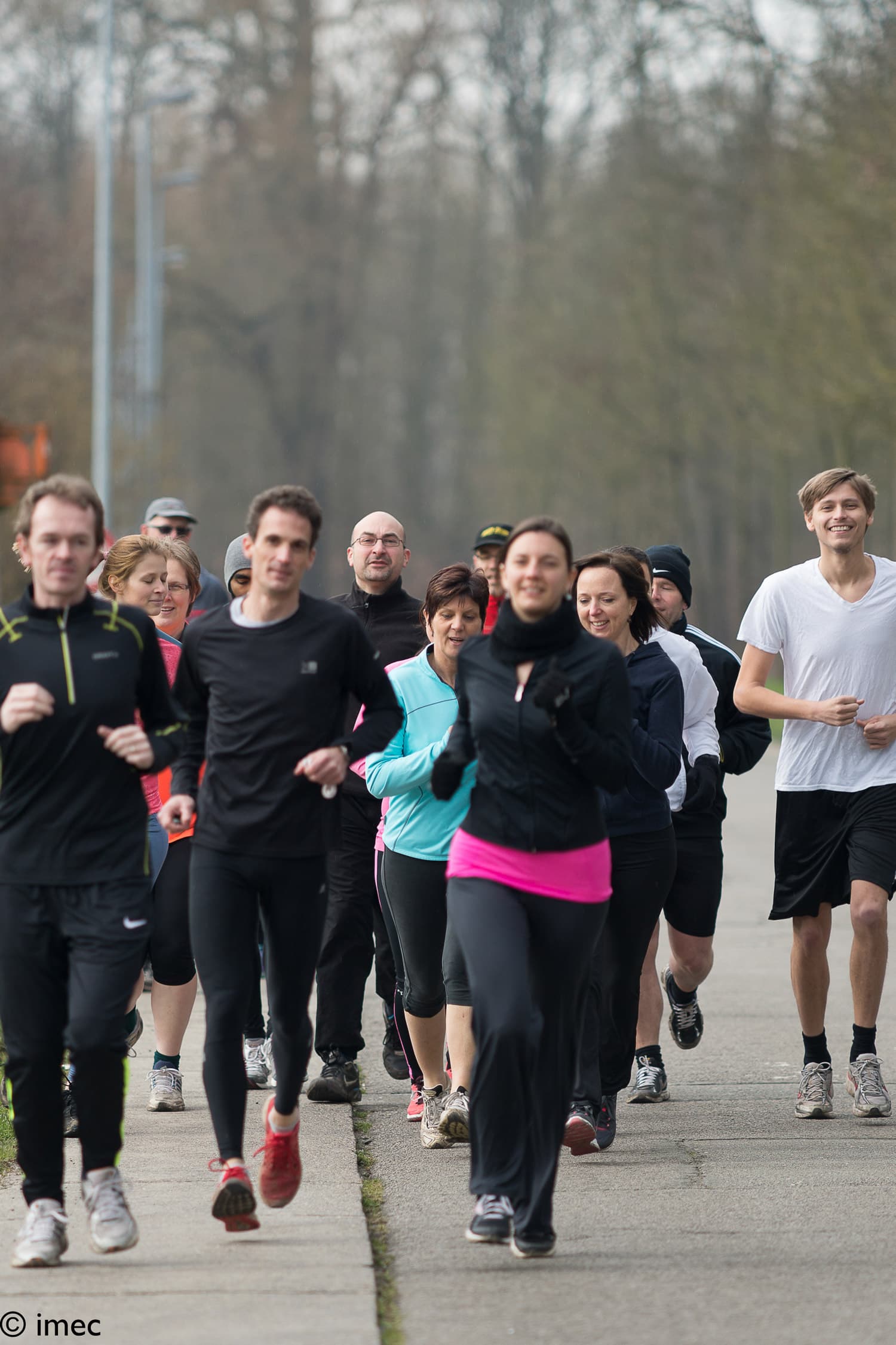 Levensloop-2 Group of employees jogging together outdoors on a path, with one runner in a white shirt at right.