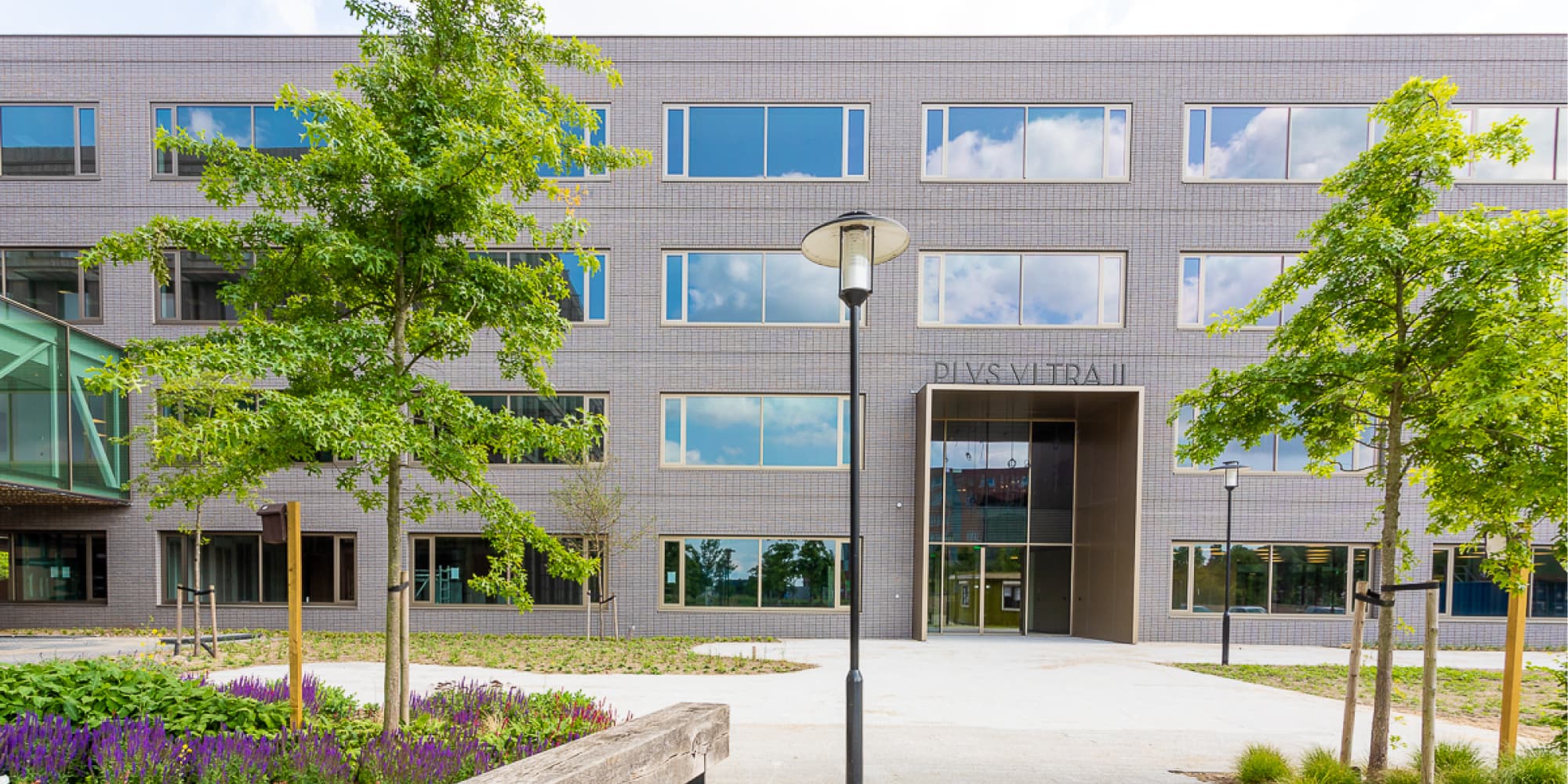 One-planet Modern research building with trees, a glass entrance, and the name “PLYS VIETRA II” above the door.