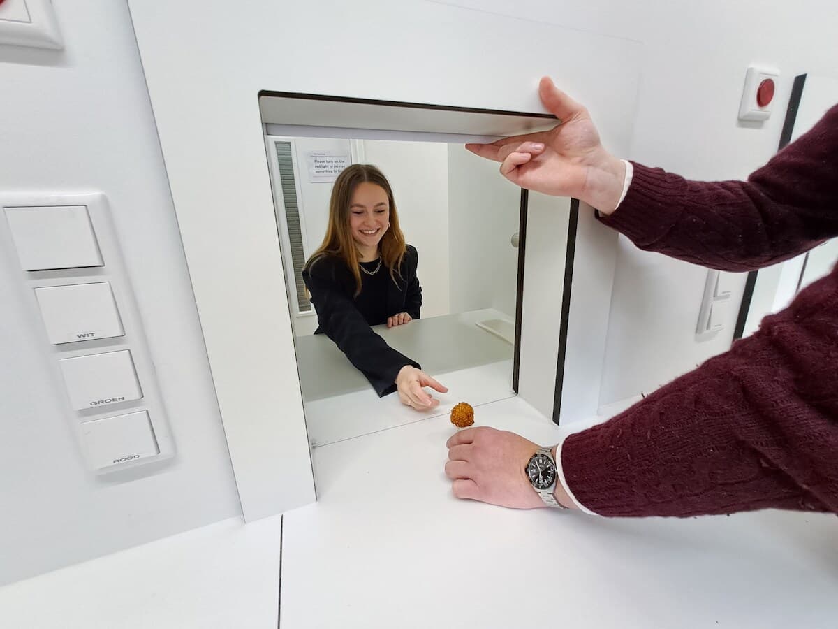 OpenEd Student handing an object through a cleanroom pass-through window