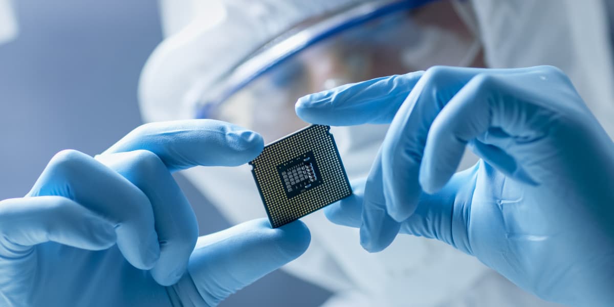 Researchers Gloved researcher holding a semiconductor chip in a cleanroom