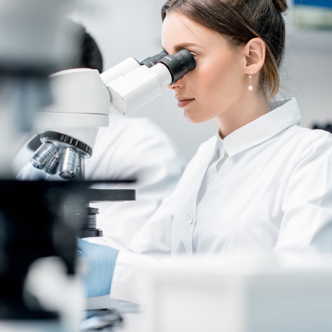 Students Researcher in a lab coat looking through a microscope
