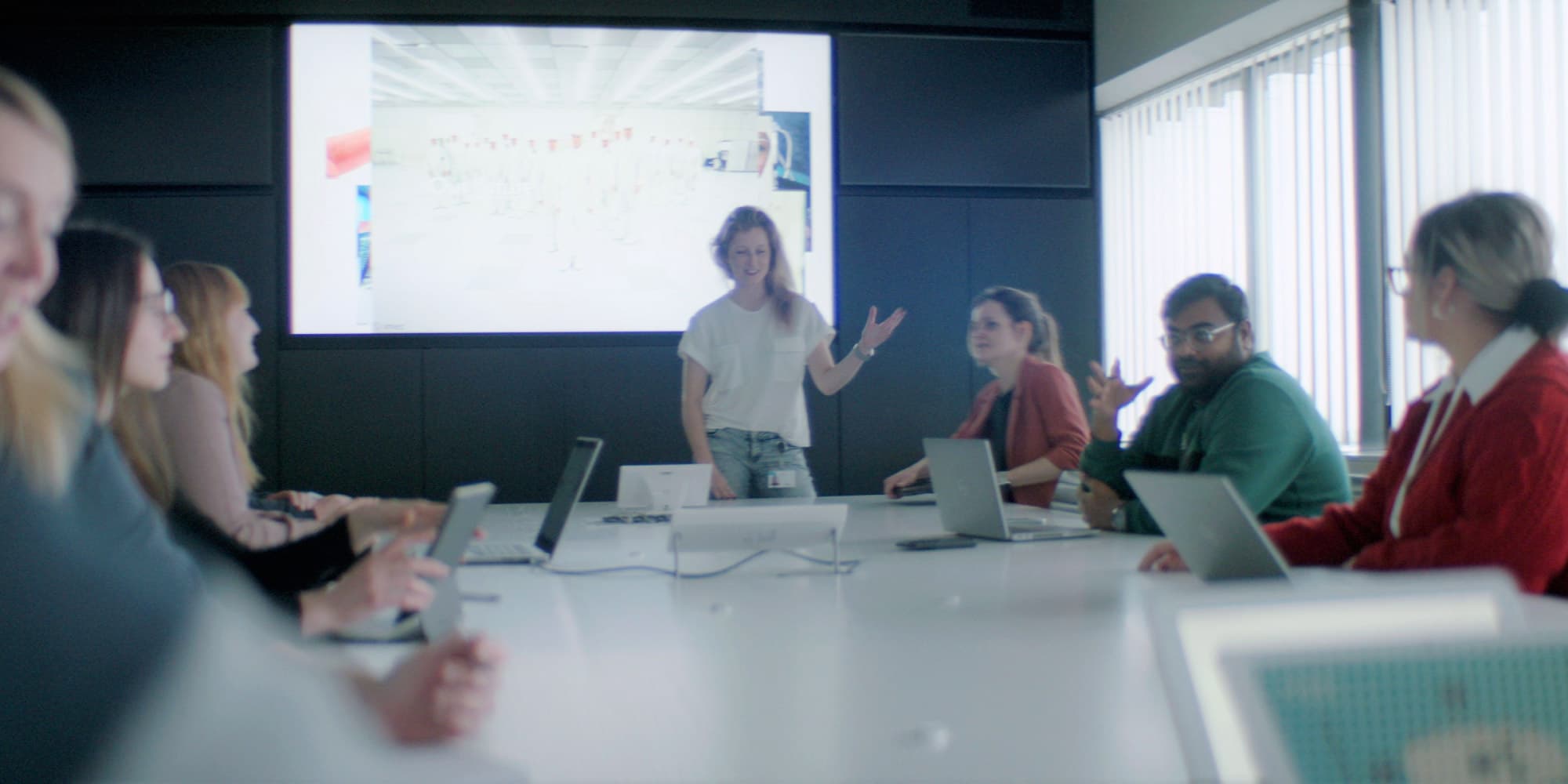 Banner-benefits Team meeting in a conference room with a presenter at the front and laptops on the table
