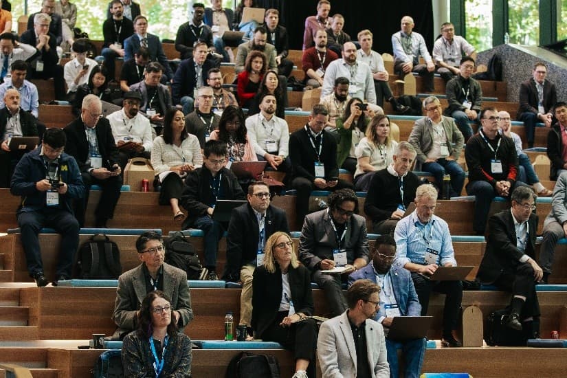 mstar%20event Audience seated in a lecture hall at an Mstar event, listening and taking notes